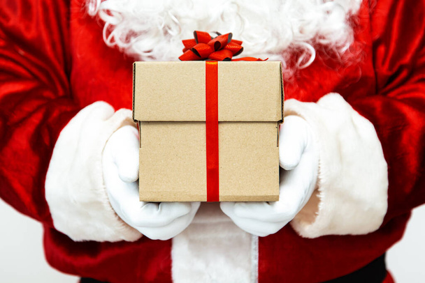 Santa claus gloved hands holding a gift box with red ribbon.  - Fotoğraf, Görsel