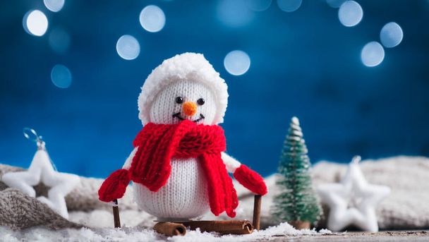 Egy boldog kötött hóember téli díszítésben fahéjas botokból készült síléceken. Karácsonyi kártya. - Fotó, kép