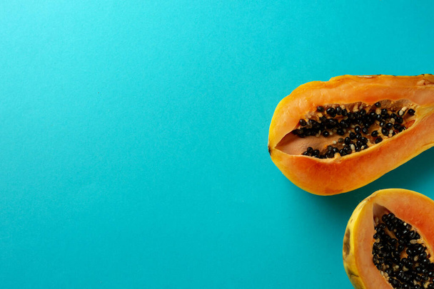 Summer composition. Tropical papaya fruits cut in half lie on a blue background. Summer concept. Flat lay, top view, copy space. - Фото, зображення