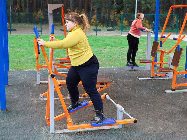 肥満の女の子は屋外ストリートシミュレータ上でスポーツ演習を実行します - 写真・画像