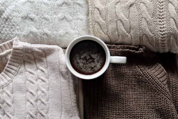 Taza de café negro sobre fondo de suéteres de lana en casa. Primer plano, enfoque selectivo y espacio de copia - Foto, imagen