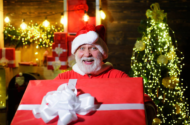 Happy man in santa costume with Christmas gift. Smiling Santa Claus with big present. Delivery service. - Photo, Image