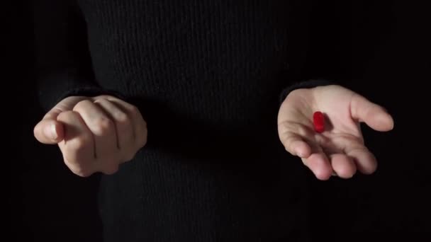 Päätöksenteon käsite. Tarjoaa punaista tai sinistä pilleriä. Ihmisen käsissä on punaisia ja sinisiä pillereitä. Tumma tausta. Studio ampui 4K kuvamateriaalia - Materiaali, video