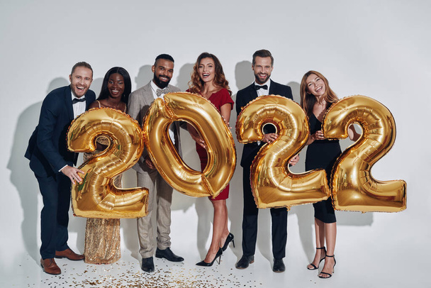 Group of beautiful people in formalwear carrying gold colored numbers and smiling - Foto, Bild