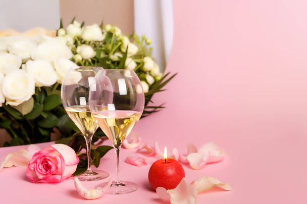 Piękne róże i dwa kieliszki białego suchego wina na różowym tle. Kompozycja romantyczna z kwiatami i winem na Walentynki lub romantyczna kolacja miłosna. Karta weselna z kwiatami i kieliszkami wina. Romantyczny nastrój i atmosfera. Francuskie białe wino. - Zdjęcie, obraz