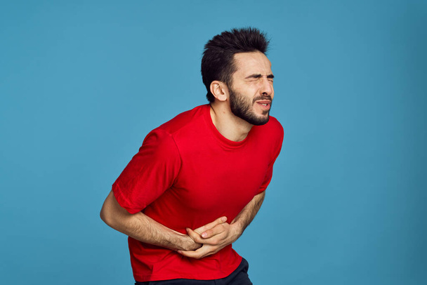 man in red t-shirt health problems emotions symptoms blue background - Φωτογραφία, εικόνα