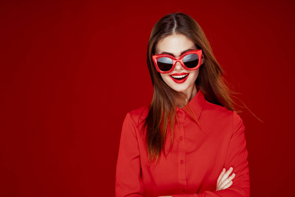 beautiful woman wearing sunglasses red shirt makeup isolated background - Foto, Bild