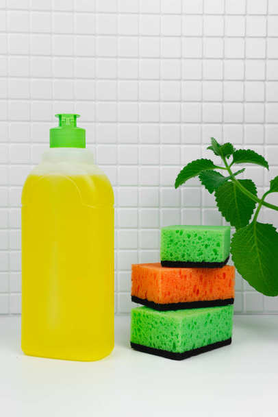 Detergent for dishes with mint and orange. Luminous aroma. Dish washing concept. Close up of  for dish washing on the kitchen countertop. House cleaning routine - 写真・画像