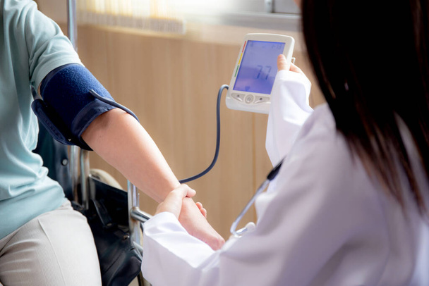 病院での脈拍の健康と検査のための患者高齢者との均一な血圧を測定する医師の女性,医師と医療,民族の多様性,医療概念. - 写真・画像