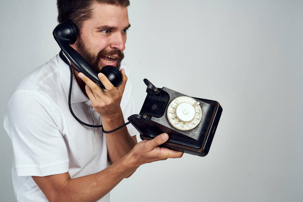 emotional bearded man talking on retro phone light background - Fotografie, Obrázek