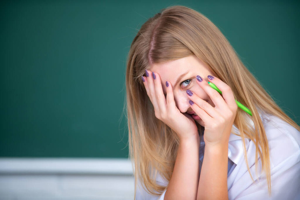 Portrait of young female college shame embarrassed student classroom on class with blackboard background. - Photo, image