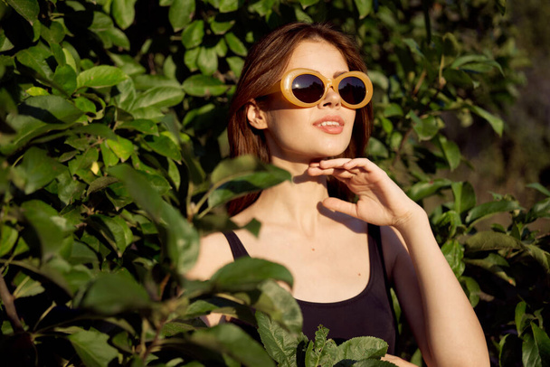 femme gaie portant des lunettes de soleil feuilles vertes nature été posant - Photo, image