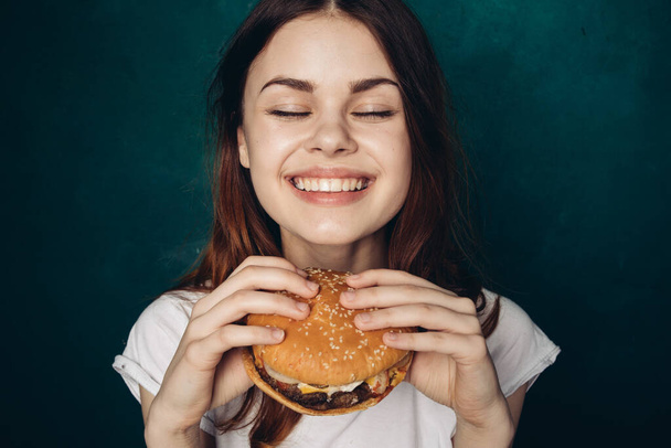 cheerful woman with hamburger near face snacking fast food - Fotoğraf, Görsel