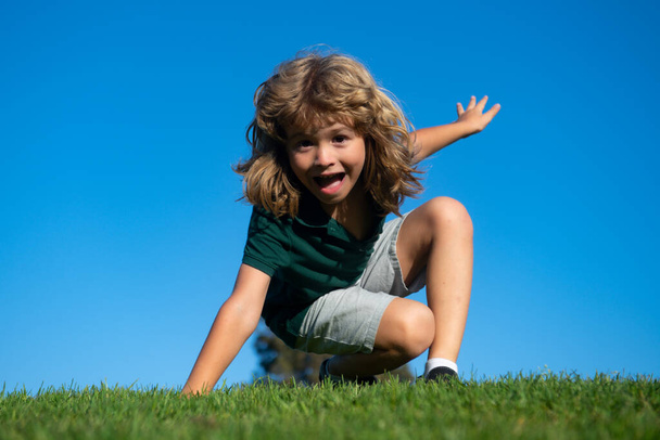 Happy little blond child laying on the grass in the park. Smmer day during school holidays. Amazed kid boy dreaming and smiling outdoor. - Fotoğraf, Görsel