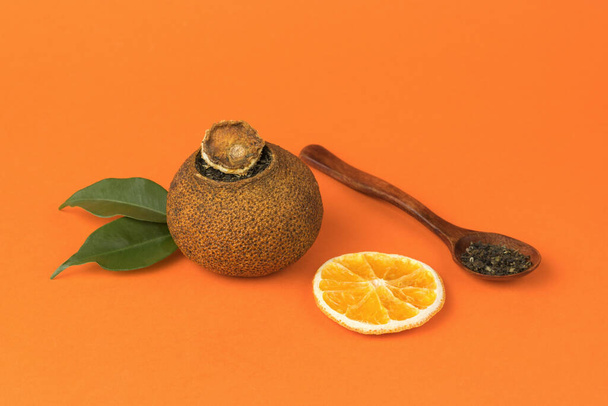 Gedroogde sinaasappels thee en een houten lepel op een oranje achtergrond. Theedrank met citrusvruchten en fruit. - Foto, afbeelding