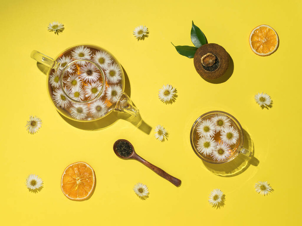 Πορτοκαλί τσάι με λουλούδια και συστατικά σε κίτρινο φόντο. Τσάι ποτό με εσπεριδοειδή και φρούτα. Επίπεδη. - Φωτογραφία, εικόνα