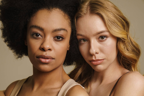 Two diverse young women in underwear standing over beige background close up - Foto, afbeelding