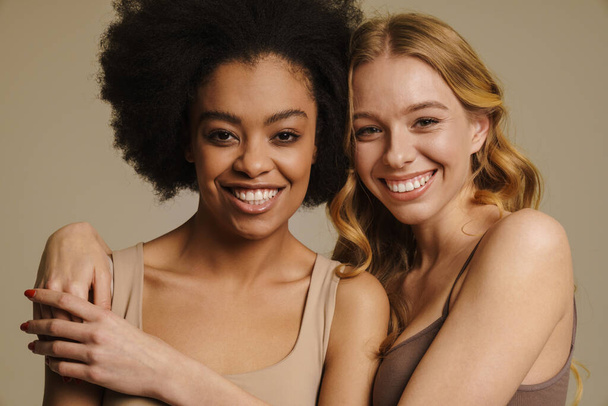 Two diverse young women in underwear standing over beige background close up - Valokuva, kuva