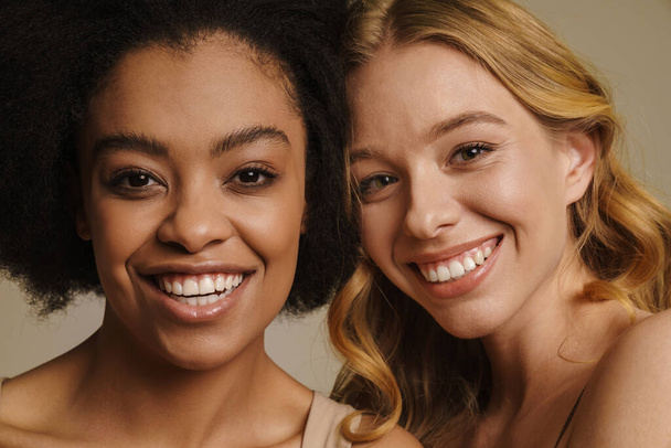 Two diverse young women in underwear standing over beige background close up - Fotografie, Obrázek