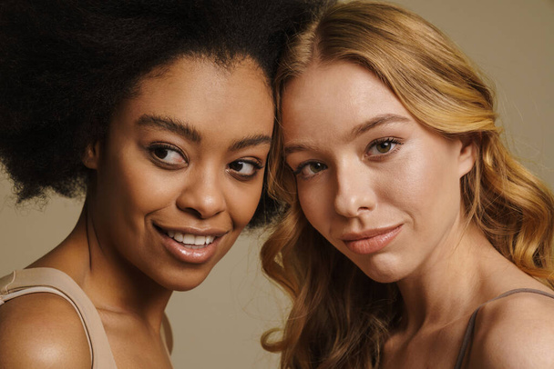 Two diverse young women in underwear standing over beige background close up - Photo, Image