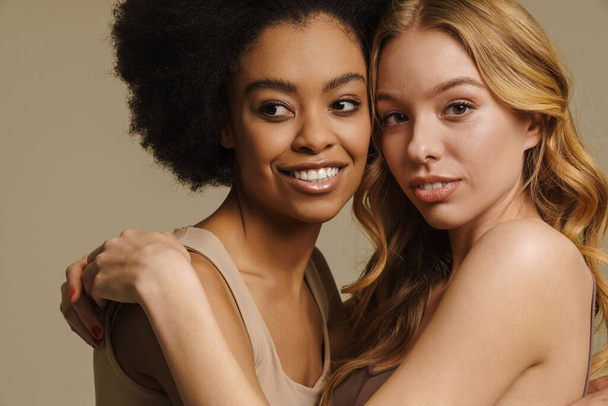 Two diverse young women in underwear standing over beige background close up - Φωτογραφία, εικόνα