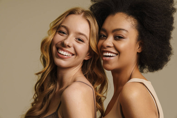 Two diverse young women in underwear standing over beige background close up - Fotografie, Obrázek