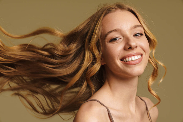 Smiling happy young white woman in underwear with long blonde curly hair standing over beige background close up - Φωτογραφία, εικόνα