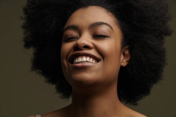 Close up of an african smiling young woman with short hair wearing underwear standing over dark background - Foto, immagini