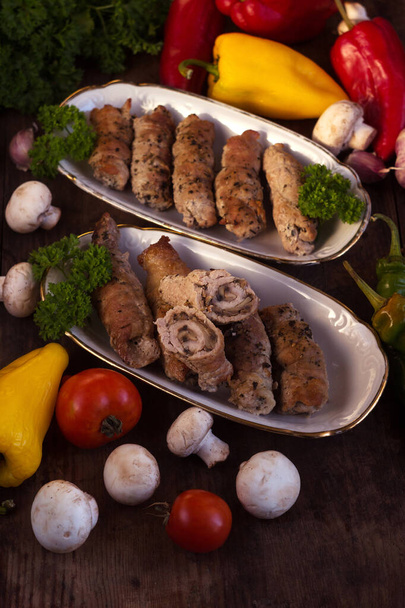Свинина з грибами, м'ясні булочки, оточені зеленню та овочами. Українські страви називаються креченікі. - Фото, зображення