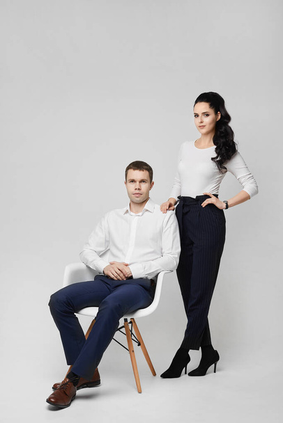 Fashionable colleagues in business, young confident man in formal clothes and gorgeous young woman on the grey background - Фото, изображение