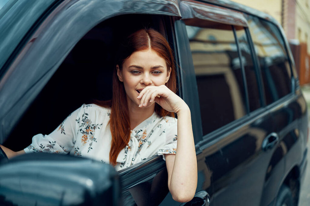 cheerful woman driving a car looks out of the window - Φωτογραφία, εικόνα