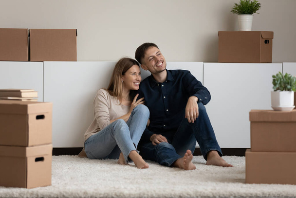 Dreamy smiling couple looking in distance, enjoying moving day - Photo, Image