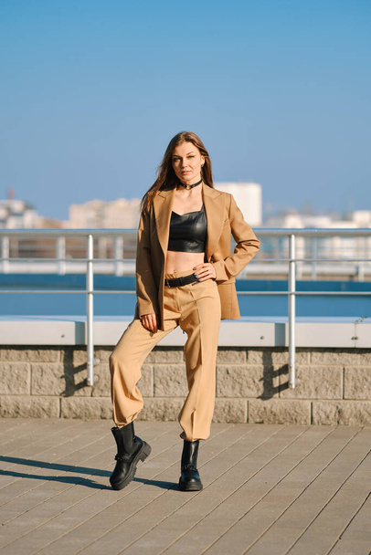 Street fashion, women casual and trendy outfit. Woman in pantsuit, leather tank-top and rough boots outdoor. - Valokuva, kuva