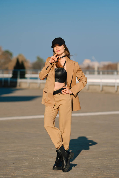 Street fashion, women casual and trendy outfit. Woman in pantsuit, leather tank-top and rough boots outdoor. - 写真・画像