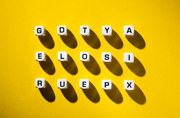 Witte blokjes met willekeurig verspreide letters op een gele achtergrond - Foto, afbeelding