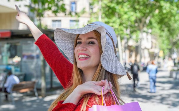 Ευτυχισμένη γυναίκα που επισκέπτονται την πόλη το καλοκαίρι φορώντας άχυρο καπέλο. - Φωτογραφία, εικόνα