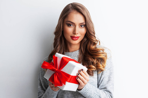 Picture of lovely casual woman with present box with red ribbon bow - Foto, Imagen