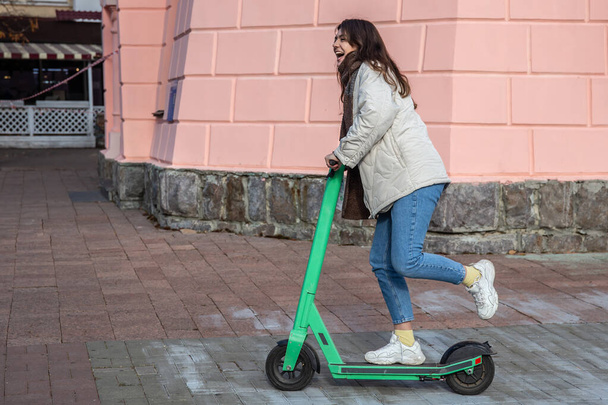 Gelukkig jong vrouw op elektrische scooter in de stad. - Foto, afbeelding