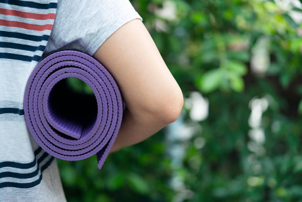 Young woman holding a yoga mat in exercise class for a sport and healthy concept - Фото, зображення