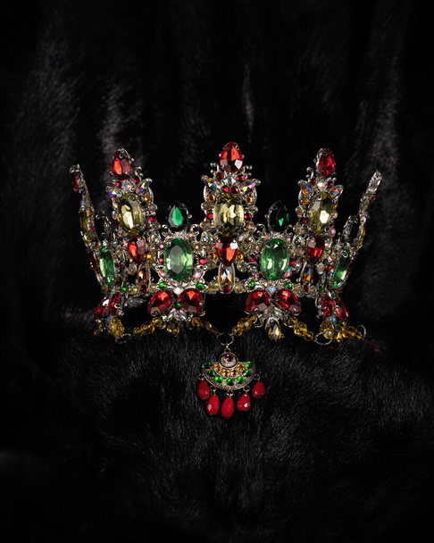hermosa corona con piedras de colores, bijouterie, para un concurso de belleza sobre un fondo negro, tocado accesorio, primer plano - Foto, Imagen