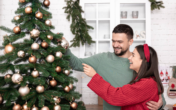 Happy married couple is decorating a Christmas tree on the eve of Christmas. - Valokuva, kuva