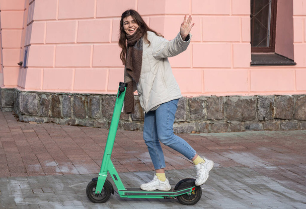 市内の電動スクーターの幸せな若い女性. - 写真・画像