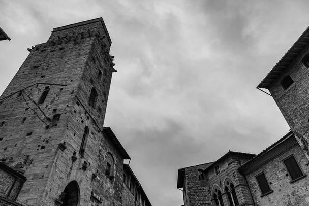 San Gimignano egy város Toszkánában. A 13. századi falakkal körülvett történelmi központ központja a Piazza della Cisterna. A középkori tornyok égboltján áll a Torre Grossa kőbe vésve. - Fotó, kép