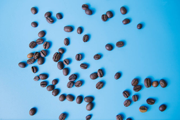 top view of coffee beans poured on a blue background, copy space - Foto, immagini