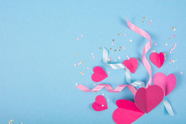 Abstrakter Hintergrund mit Papierherzen, Schleifen zum Valentinstag. Blauer Liebes- und Gefühlshintergrund für Poster, Banner, Post, Karte. Studioaufnahme - Foto, Bild