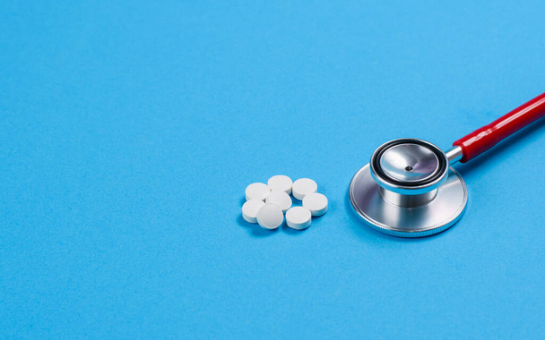 Medizinprodukt und ein Stapel Pillen auf blauem Hintergrund. Selektive Fokussierung. - Foto, Bild