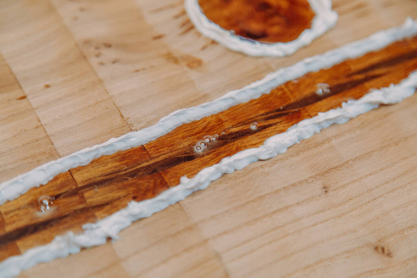 Résine époxyde séchée dans une table en bois, macro gros plan. Processus de fabrication d'une résine artisanale et d'une table en bois - Photo, image