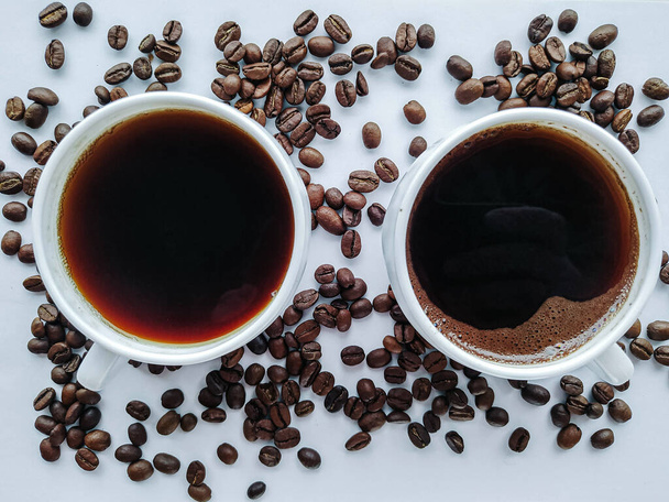 Две чашки белого кофе с кофейными зернами на белом фоне - Фото, изображение