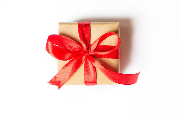  Urlaubskonzept - isoliertes Geschenk mit roter Schleife auf weißem Hintergrund. Komposition für Weihnachten, Neujahr und Feiertage. flache Liege mit Platz für Text. - Foto, Bild
