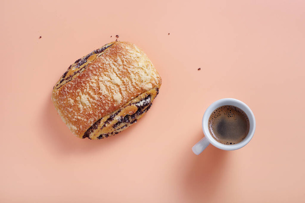 Sweet bun with poppy seeds and cup of coffee on color background, top view  - Fotó, kép
